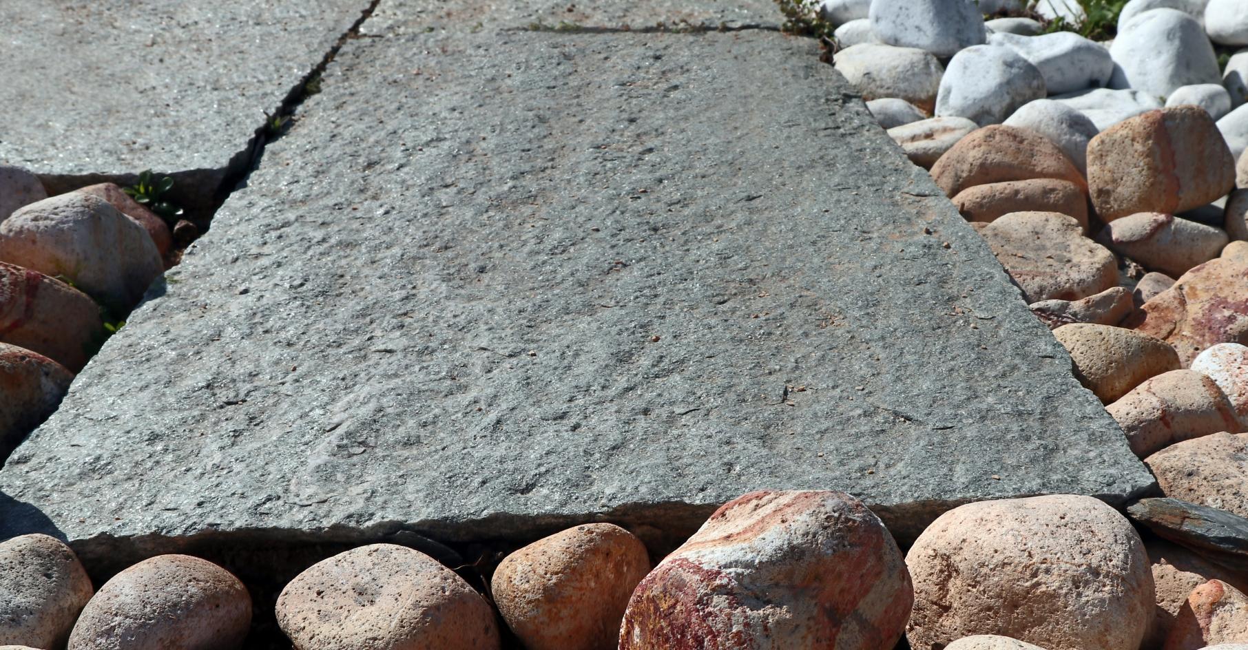 Dalle en pierre de Luzerne grise entourée de galets arc-en-ciel